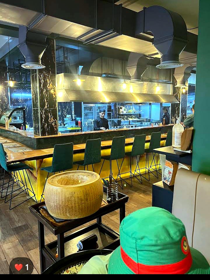 Cuisine ouverte de La Raviole, meule de parmesan et brigade en service